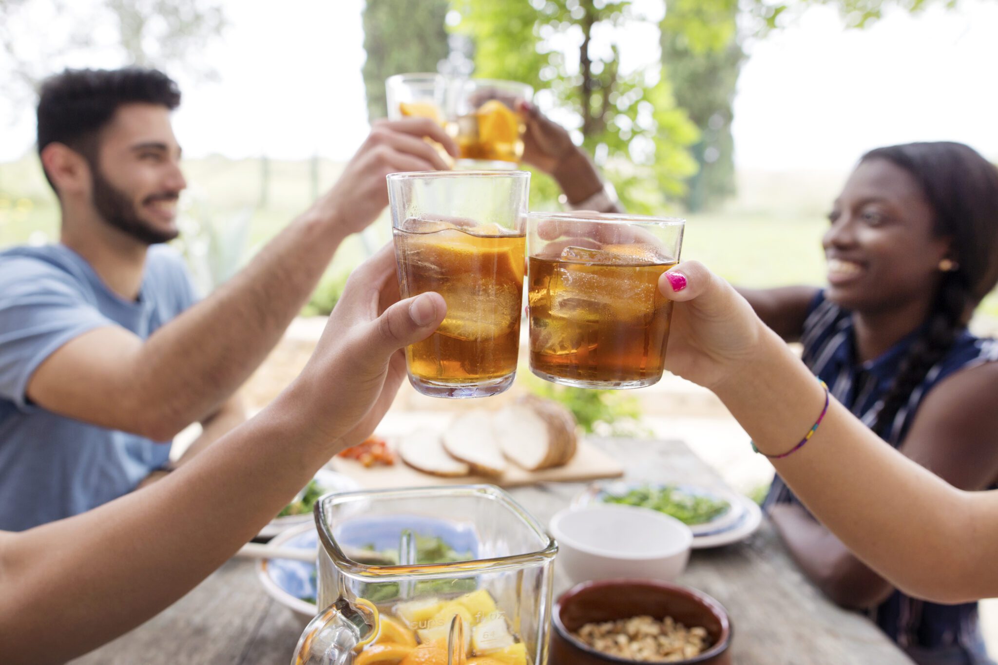 Friends Toasting Iced Tea Glasses At Outdoor Table