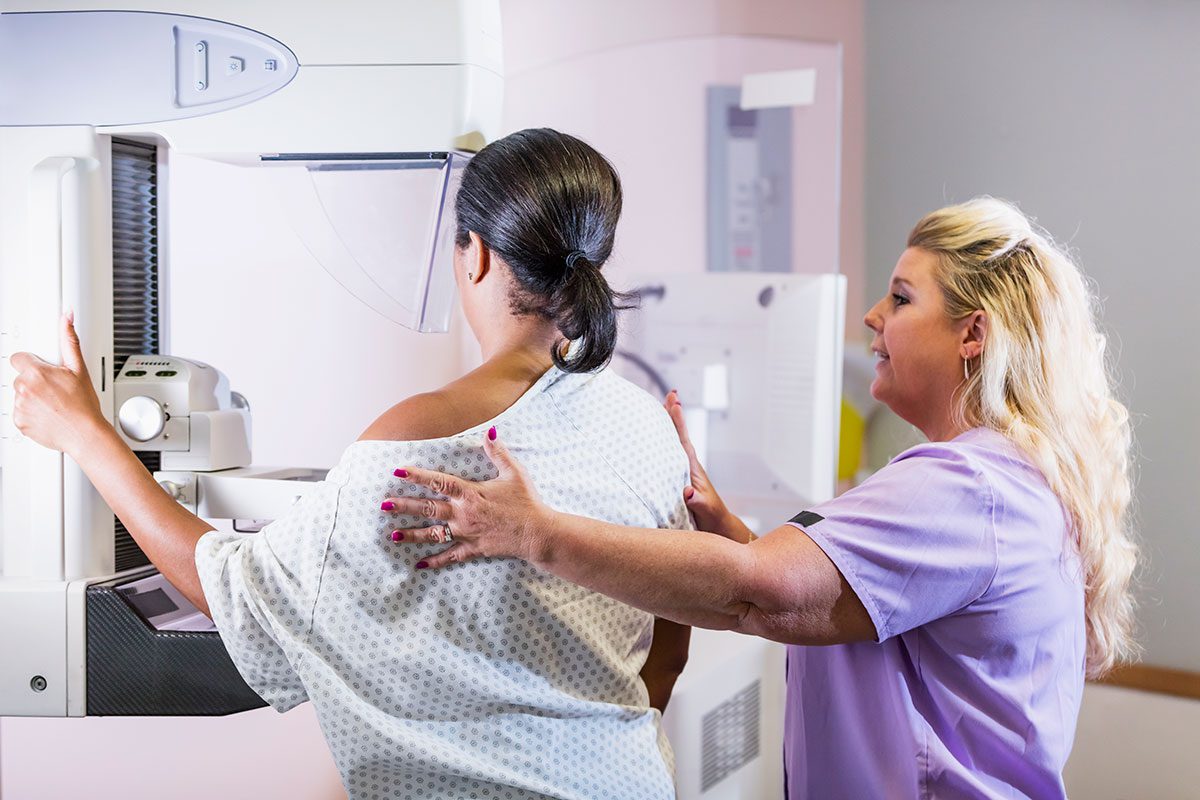 Mammogram machine in use with woman and technician